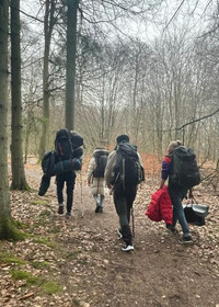 Människor som går i skogen med ryggsäckar