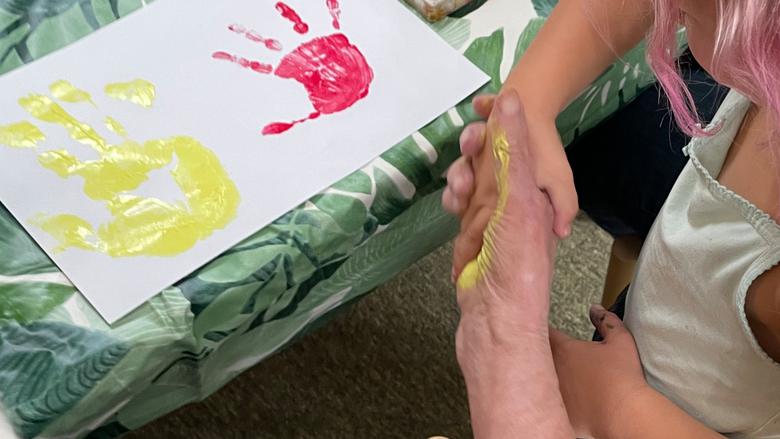 Äldre kvinna och barn målar händer i olika färger tillsammans