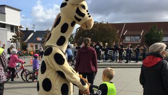 En giraff maskot träffar barn på torget