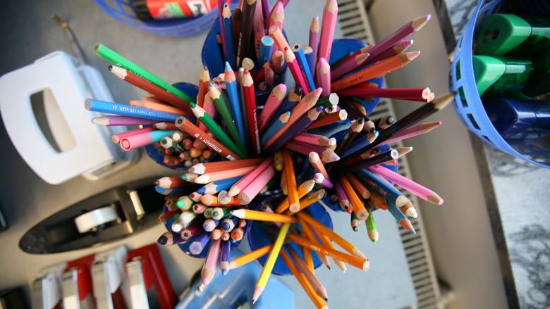 Massor av pennor som står i olika muggar sett uppifrån.
