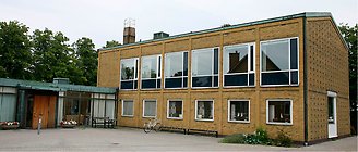 Medborgarhuset. Brun tegelbyggnad i två våningar med fönster mot parkering