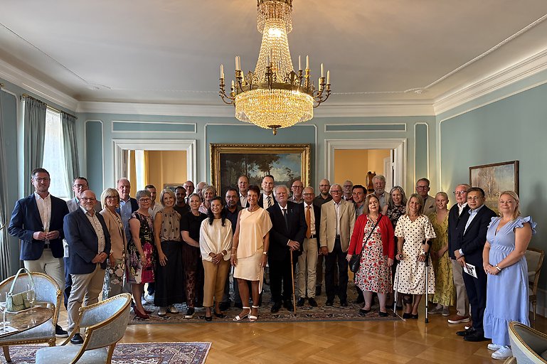 Gruppbild på människor i en fin sal med kristallkrona